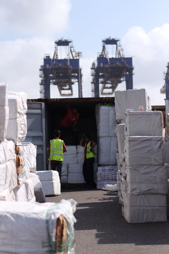 Home Dock workers loading cargo at Karachi Port with visible cranes and containers.