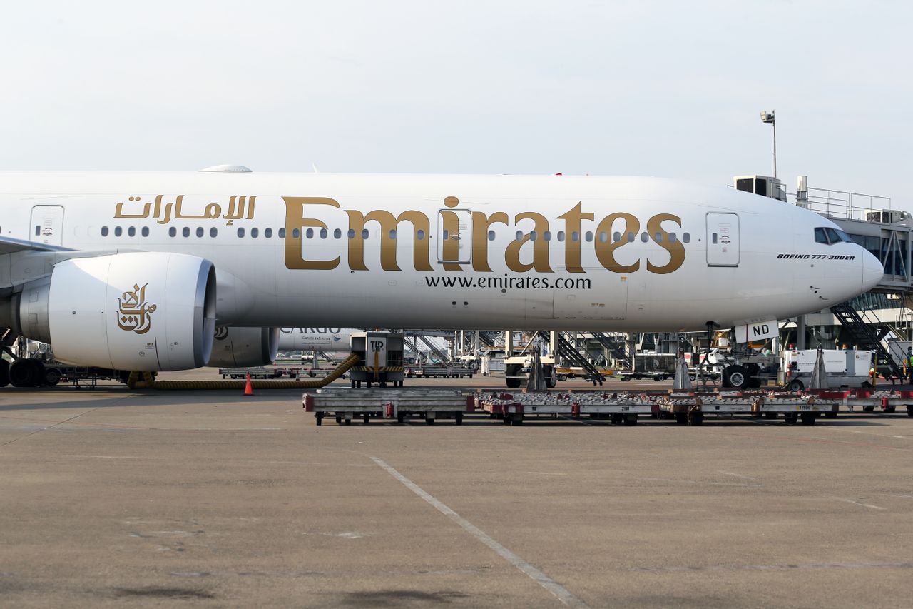 Emirates Boeing 777 on the tarmac during day at a bustling airport.